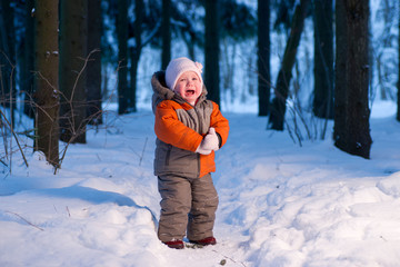 Cute adorable baby cry on snow road in winter forest at evening