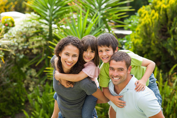 Mother and father giving children a piggyback