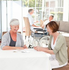 Senior women playing cards while their husbands are talking