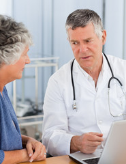 Fototapeta premium A senior doctor with his patient looking at the laptop