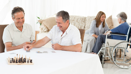 Men playing cards while their wifes are talking