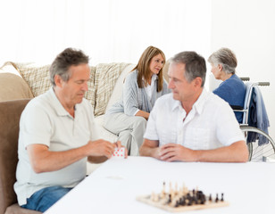 Men playing cards while their wifes are talking