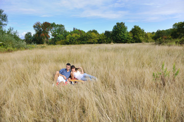 happy couple enjoying countryside picnic in long grass