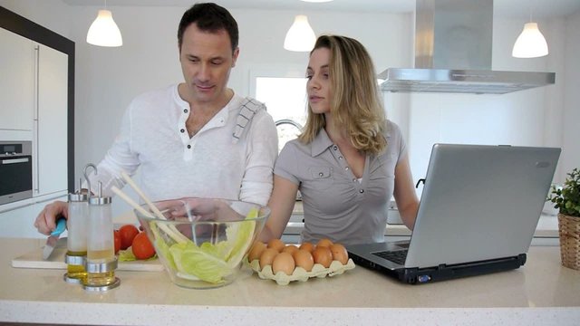 Couple in kitchen checking recipe