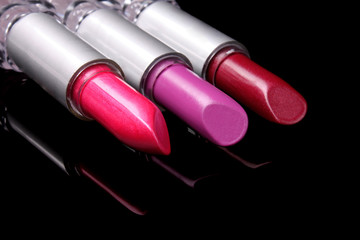 three bright lipsticks on a black background