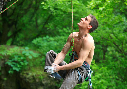 Tired rock climber hanging on rope