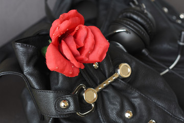 Red Rose of plastic on a black leather bag