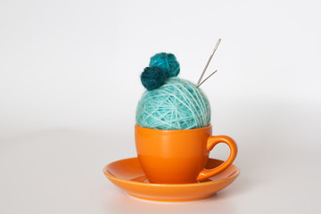 Orange cup with balls of yarn
