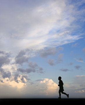 Silhouette of single male jogger against stunning blue sky