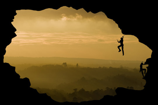 Two rock climbers silhouette against stunning sunset landscape c