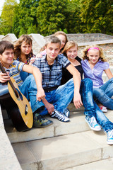 Obraz premium Teenage friends sitting on stairs