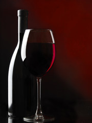 Bottle and glass against a black background with rim lighting