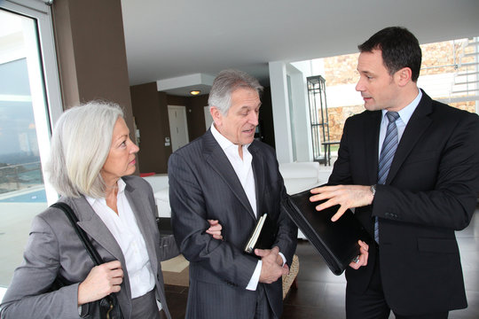 Senior couple visiting modern house with real-estate agent