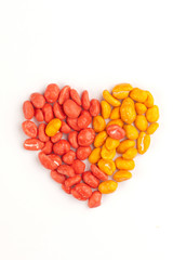 Red and yellow dragees of peanuts in a shape of a heart