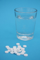 Tabletten, Wasserglas mit blauem Hintergrund