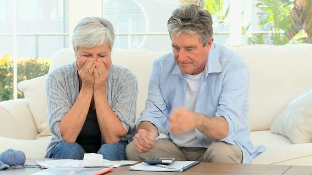 Elderly couple calculating their bills in the living room