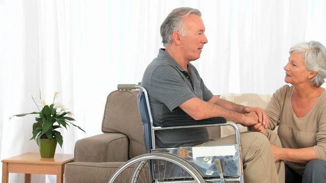Man in a wheelchair talking to his wife at home