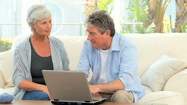 Aged couple talking in front of a computer in the living room