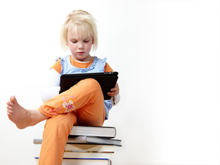 Cute blond child is reading on touchpad