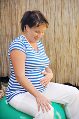 Pregnant young woman exercising with ball