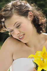 Young bride looking down and holding lilies