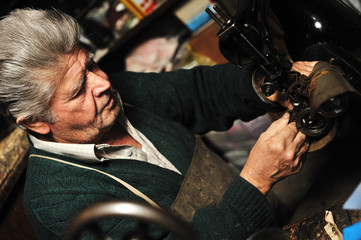 Senior man working with old machine in his own workshop