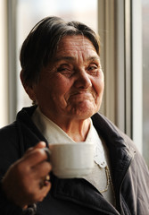 Portrait of Happy Senior Woman Beside the Window with Coffee