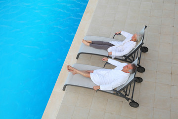 Senior couple relaxing in long chairs