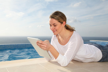 Woman using electronic tablet by swimming pool