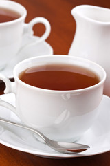 Black tea in mugs with saucers