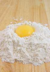 Egg yolk on flour on wooden background