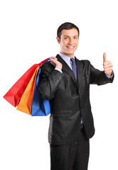 A happy male holding shopping bags and giving thumb up