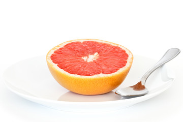 half grapefruit on plate with spoon