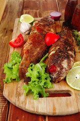 main portion of two grilled fish served on wood