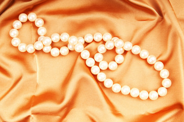 Pearl necklace on the bright satin background