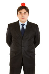Young businessman with apple on his head isolated on white.