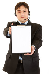Smiling young businessman with headset holding blank clipboard