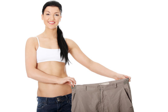 Young happy woman showing how much weight she lost