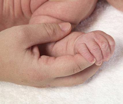 Small baby hand holding onto mother's finger