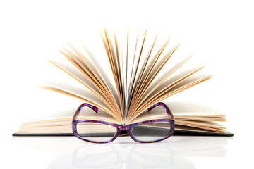 open book with reading glasses over white background