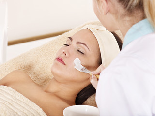 Beautician applying  facial mask by  woman.