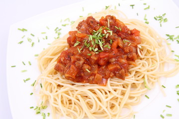 Spaghetti bolognese on a plate decorated with some chives
