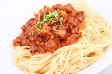 Spaghetti bolognese on a plate decorated with some chives
