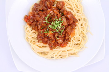 Spaghetti bolognese on a plate decorated with some chives