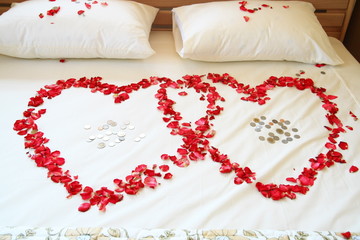 Red rose hearts on white bed.