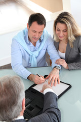 Happy couple signing purchase contract with real-estate-agent