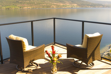 Fototapeta premium Two luxurious chairs on a lakefront sun deck