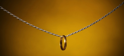 Fototapeta premium Gold ring on a silver chain;