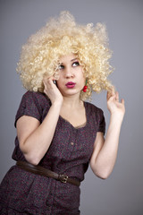 Funny girl in wig calling by phone.