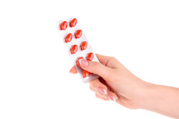 red capsules of vitamins in the hand on a white background